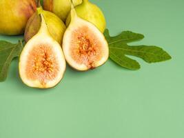 The top view of figs fruit with fresh leaves isolated green background. High Vitamins fruit. Close-up photo. Space for text. Concept of healthy fruits and healthcare photo