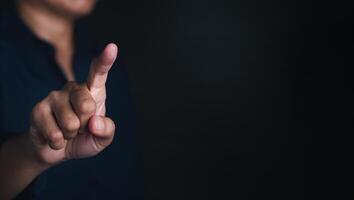 Businessman in front of visual touch screen or pointing to something on black background with space for text photo