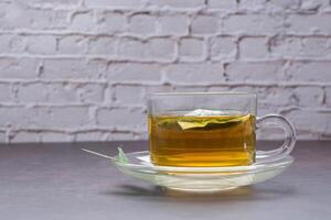 A cup of hemp tea on vintage background with a white brick wall. Cannabis herbal tea. Close-up photo. Selective focus. Healthy beverage and relaxation concept photo
