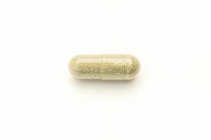 Close-up of Andrographis paniculata capsule placed isolated on white background. Space for text. Herbal, medicine, and healthcare concept photo