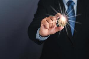 A businessman's hand holds a bitcoin coin with sunlight effect on a gray background. Space for text. Future money concept and virtual cryptocurrency photo