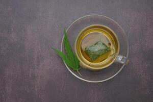 A cup of hemp tea laid on vintage background. Cannabis herbal tea. Close-up photo. Space for text. Relaxation concept photo