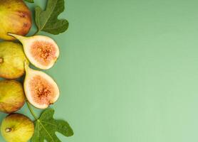 The top view of figs fruit is placed with fresh leaves isolated green background. High Vitamins fruit. Close-up photo. Space for text. Concept of healthy fruits and healthcare photo