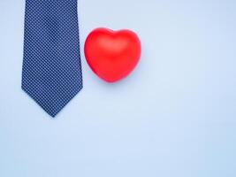 Happy Father's Day with a blue tie and red heart laid isolated on a light blue background with space for text. Top view. Flat lay photo