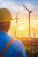 Engineer is contemplating a wind farm at sunset photo