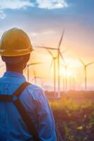 Engineer looking at wind turbines in countryside at sunset photo