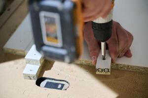 Close-Up of Worker Drilling Wooden Boards to Prepare for Further Processing photo