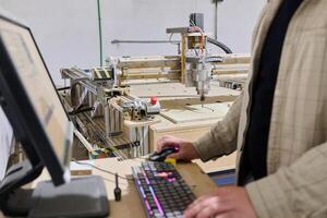Operator Entering Coordinates on Computer for CNC Machine to Precisely Cut Wooden Pieces photo