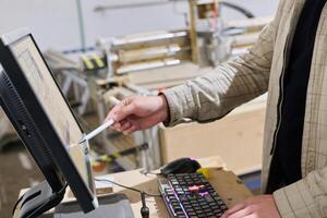 Operator Entering Coordinates on Computer for CNC Machine to Precisely Cut Wooden Pieces photo