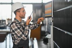 Factory male bearded worker is programming a CNC milling machine with copy space photo