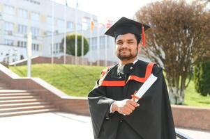Portrait of happy man, graduation or student in university campus photo