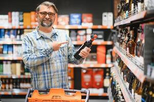 Man in a supermarket choosing the right wine photo