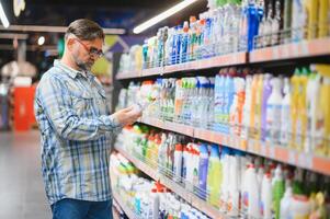 Man in the supermarket in the household chemicals department. Large selection of products photo