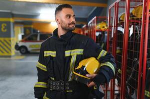 Fireman wearing protective uniform standing in fire department at fire station photo