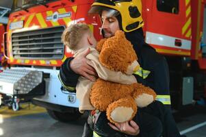 Firefighter holding child boy to save him in fire and smoke,Firemen rescue the boys from fire photo