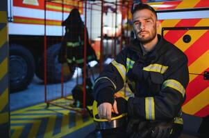 Portrait of a firefighter in a protective suit and a protective helmet standing by a fire engine after working on a fire. Close-up image photo