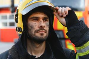 Portrait of a firefighter in a protective suit and a protective helmet standing by a fire engine after working on a fire. Close-up image photo