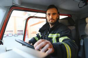 Side view of firefighter in protective uniform driving fire engine photo