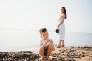 Mother and son playing on the beach at the day time. Concept of friendly family. photo