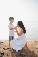 Mother and son playing on the beach at the day time. Concept of friendly family. photo