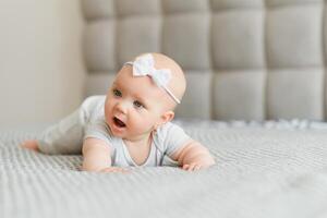 Cute happy 7 month baby girl in diaper lying and playing photo