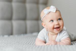 Cute happy 7 month baby girl in diaper lying and playing photo