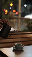 Pouring hot water into a cup on the table outdoor with colorful bokeh background at night video