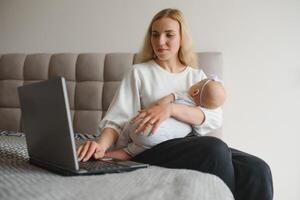young woman with a small child works from home. Working remotely during a lockdown. freelancer or remotely employed specialist is sitting on a bed with a laptop and trying to concentrate photo