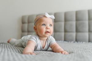 Cute happy 7 month baby girl in diaper lying and playing photo