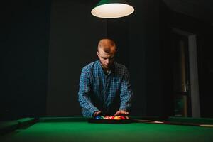 Young handsome man leaning over the table while playing snooker photo