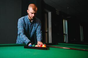 Young handsome man leaning over the table while playing snooker photo