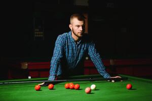 Young handsome man leaning over the table while playing snooker photo