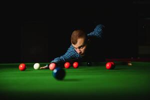 Young handsome man leaning over the table while playing snooker photo