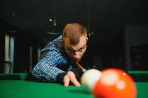 Young handsome man leaning over the table while playing snooker photo