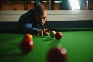 Young handsome man leaning over the table while playing snooker photo