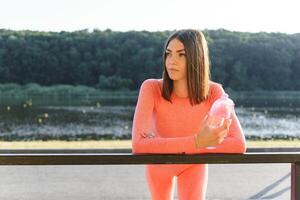 hermosa joven deportivo mujer Bebiendo agua después correr. ajuste persona que practica jogging niña tomando un descanso después deporte. estilo de vida, gente, deporte y ocio concepto. foto