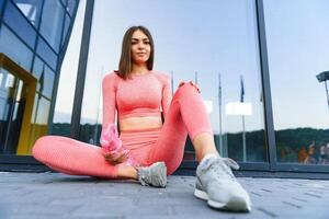hermosa joven deportivo mujer Bebiendo agua después correr. ajuste persona que practica jogging niña tomando un descanso después deporte. estilo de vida, gente, deporte y ocio concepto. foto