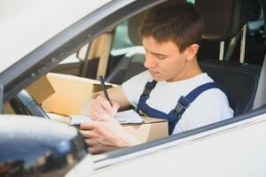 Young Delivery Man Checking List On Clipboard In car photo