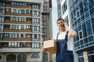 Deliveryman in uniform holds parcel and phone photo