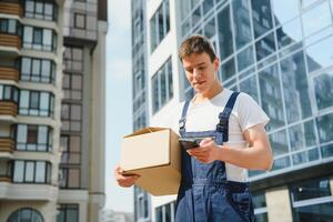 Deliveryman in uniform holds parcel and phone photo