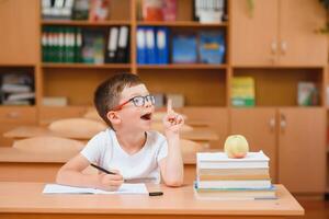 Elementary school boy at classroom desk trying to find new ideas for schoolwork. photo