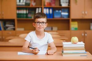 Elementary school boy at classroom desk trying to find new ideas for schoolwork. photo