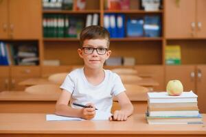 Elementary school boy at classroom desk trying to find new ideas for schoolwork. photo
