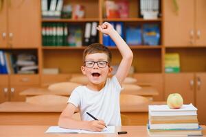 Elementary school boy at classroom desk trying to find new ideas for schoolwork. photo