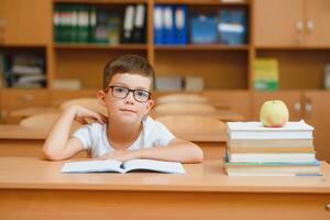 Elementary school boy at classroom desk trying to find new ideas for schoolwork. photo