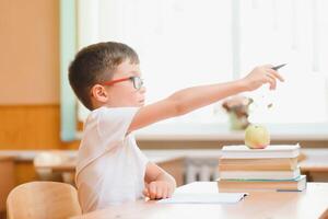 Elementary school boy at classroom desk trying to find new ideas for schoolwork. photo
