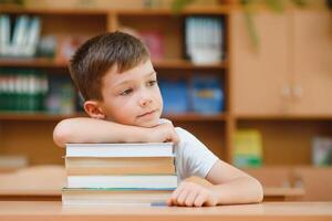 Portrait of cute boy on top of book stack. The concept of learning in primary school. photo