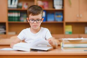 Elementary school boy at classroom desk trying to find new ideas for schoolwork. photo