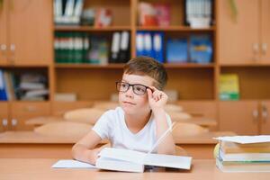 Elementary school boy at classroom desk trying to find new ideas for schoolwork. photo