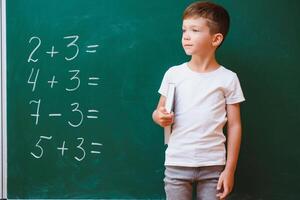 Back to school concept. School child in class. Happy kid against green blackboard. Smart child in classroom. Idea and education concept photo